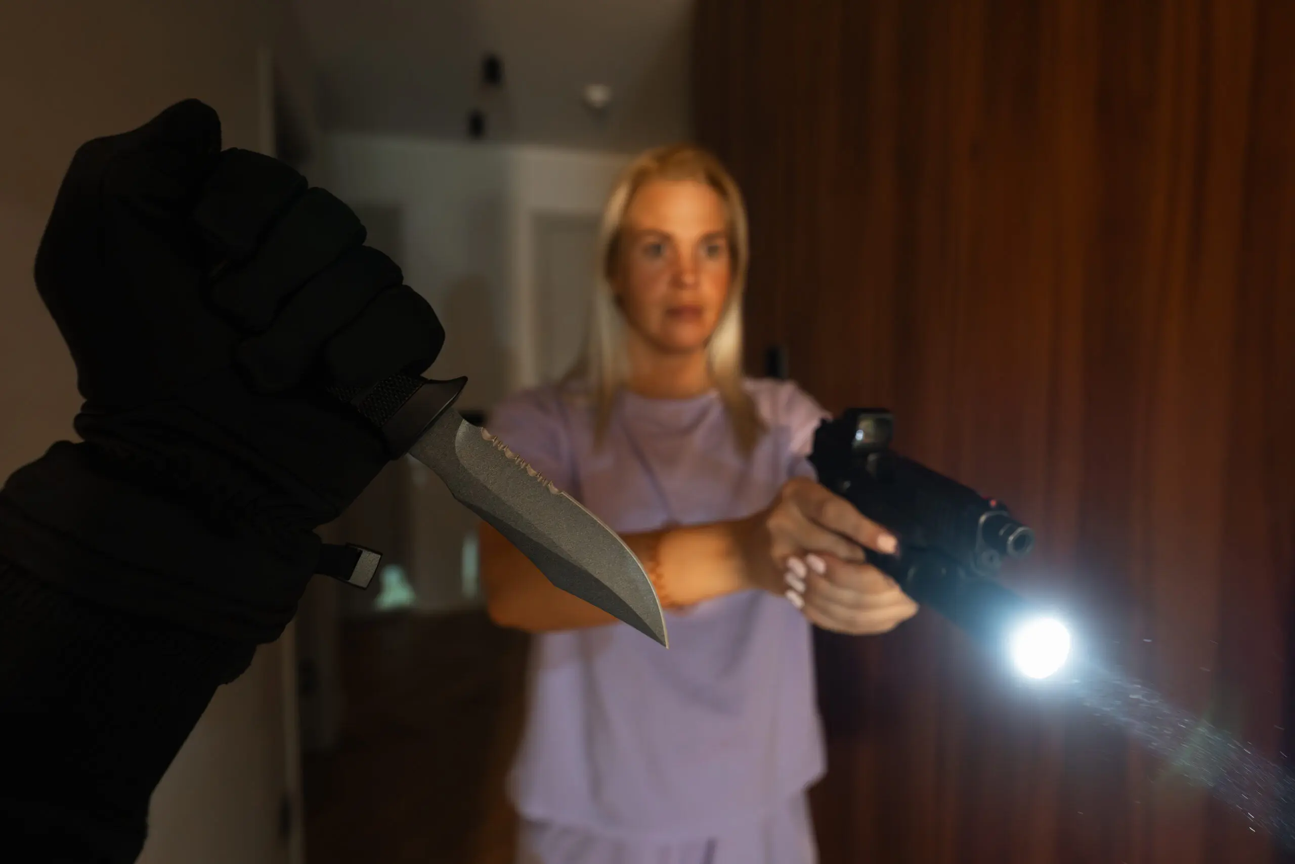 Woman with pistol and flashlight in dark home showing low light home defense concerns